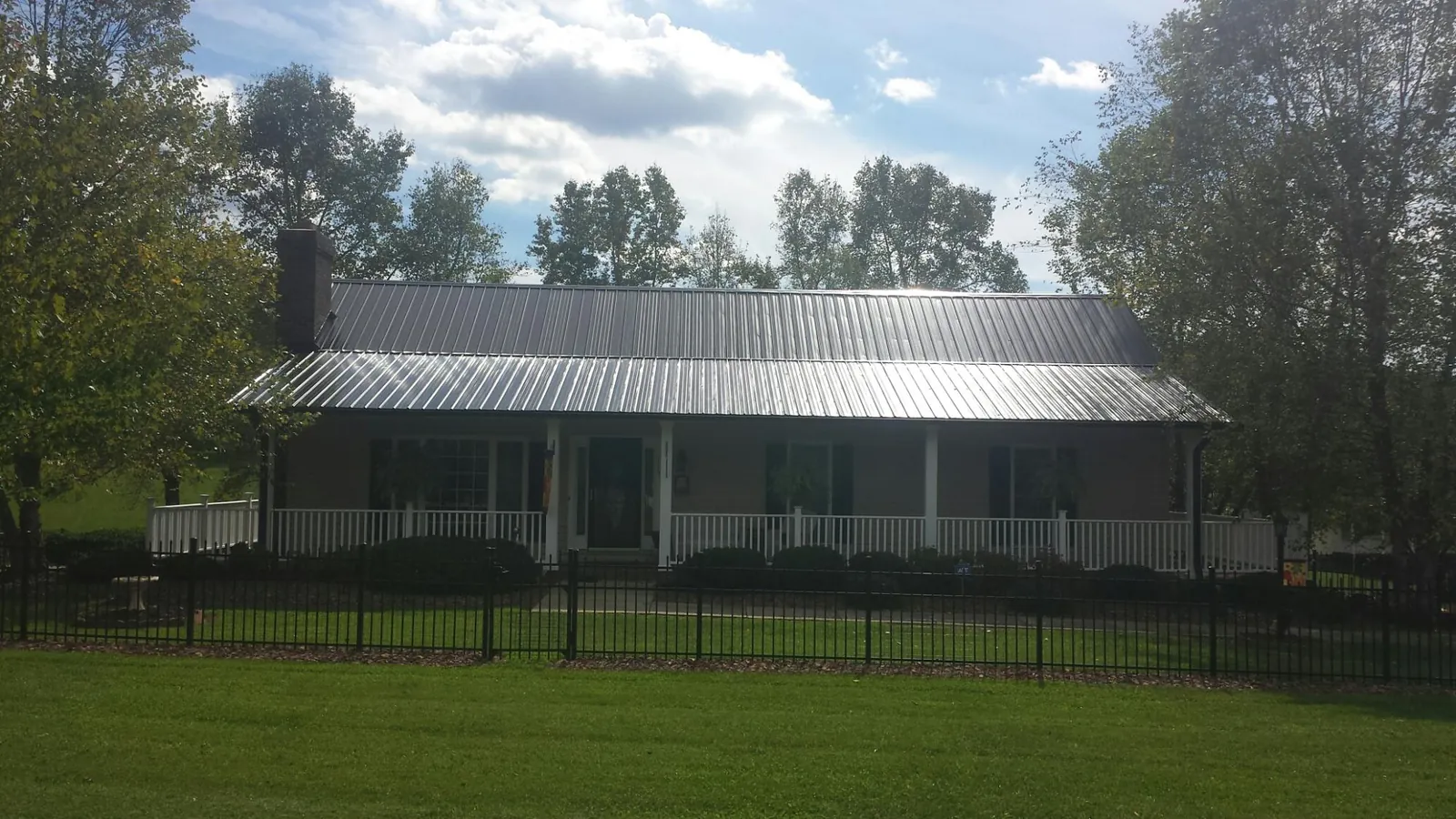 Gray metal roof on a brick ranch with a full width front porch — Gutter Guard Installation work by our crew in Vinton